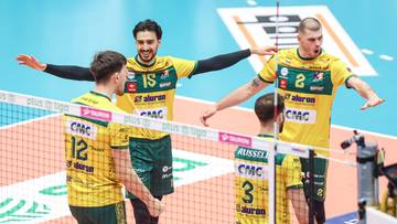 Czterech siatkarzy w żółto-zielonych strojach celebracji, jeden z nich podnosi ręce w geście zwycięstwa.