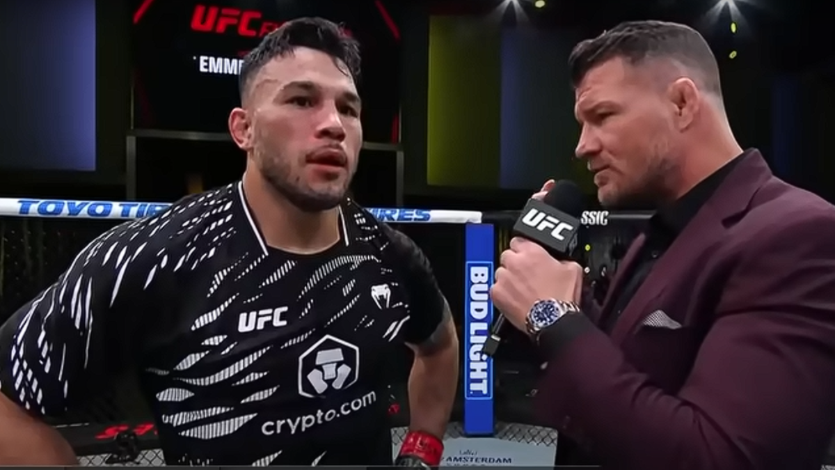 Dwóch mężczyzn na ringu UFC, jeden z nich ma na sobie czarną koszulkę z logo UFC, a drugi trzyma mikrofon i rozmawia z nim.