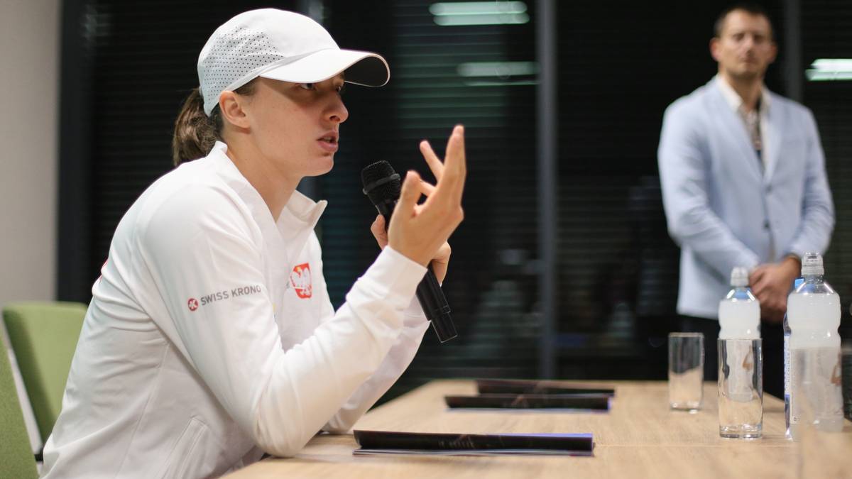 Iga Świątek przemawia do mikrofonu, wskazując palcami.