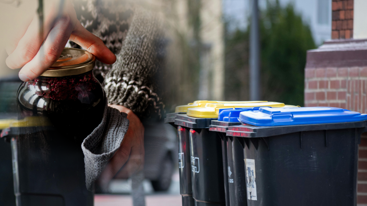 Dłoń trzymająca słoik z przetworami na tle pojemnik&oacute;w do segregacji odpad&oacute;w.