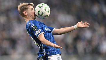 Piłkarz Lecha Poznań zagrywa piłkę głową.