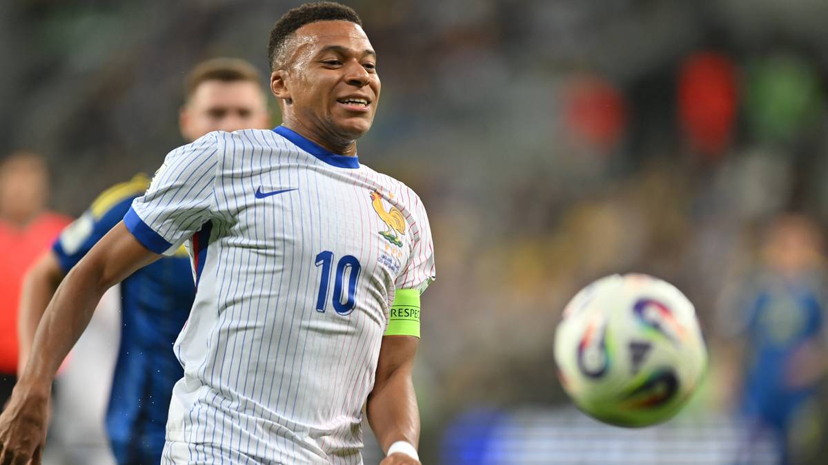 Piłkarz w białej koszulce z numerem 10, Kylian Mbappe, biegnie z piłką podczas meczu.