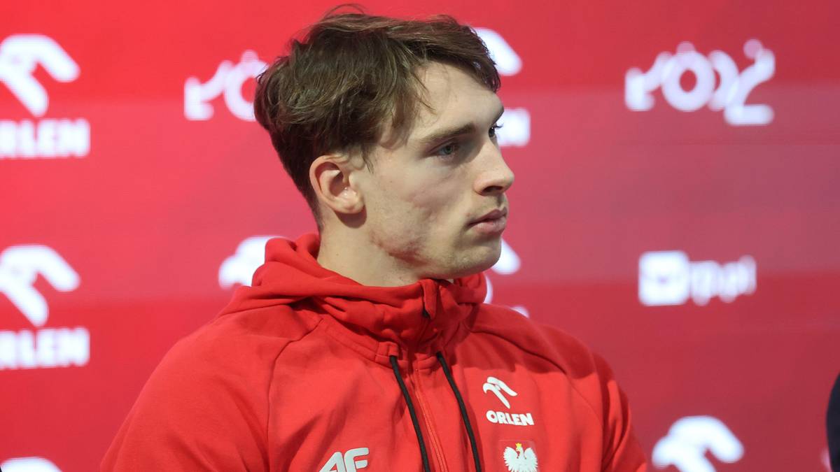 Portret młodego mężczyzny w czerwonej bluzie sportowej, patrzącego w bok.