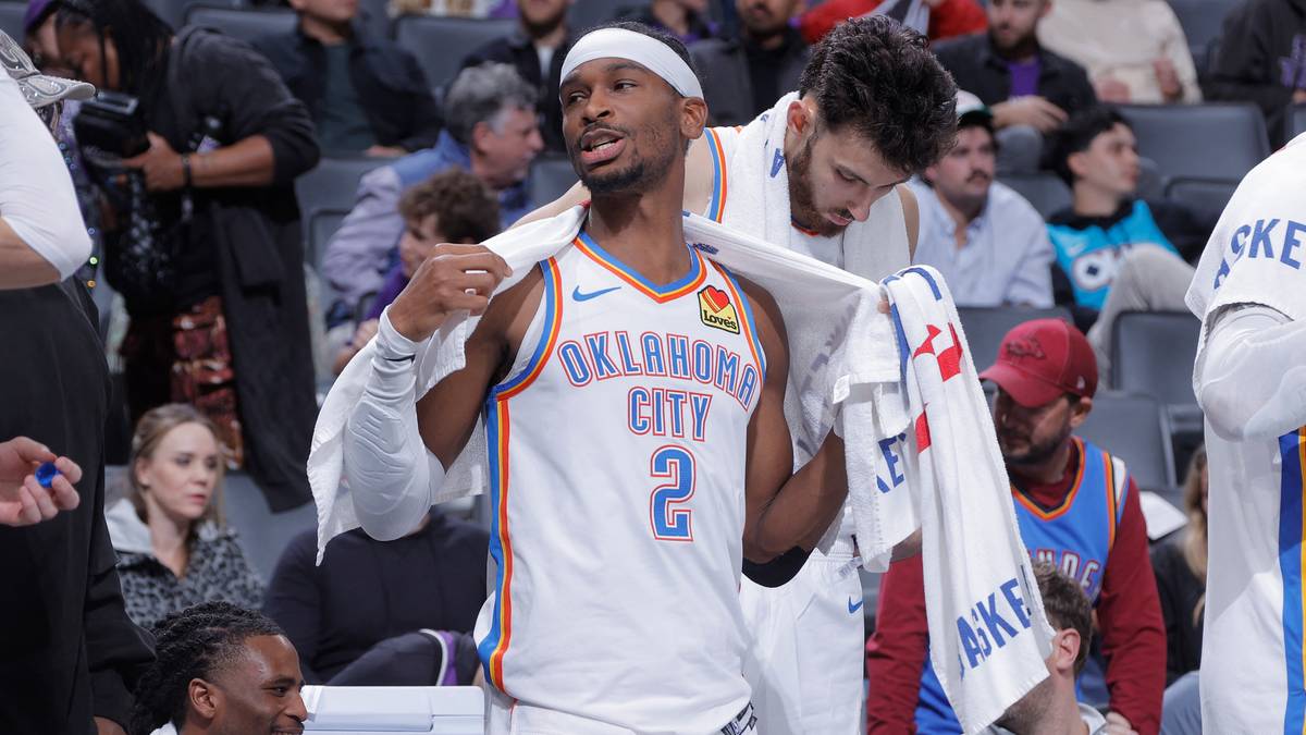 Gracz Oklahoma City Thunder w białym stroju z numerem 2 na plecach, z opaską na głowie, okrywa się ręcznikiem.