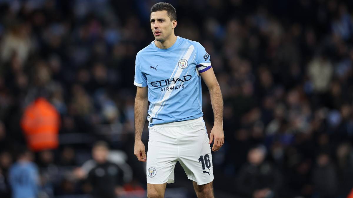 Piłkarz Manchesteru City w jasnoniebieskiej koszulce i białych spodenkach na tle publiczności.