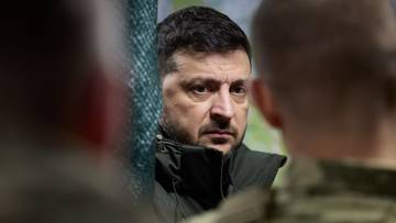 Portret Wołodymyra Zełenskiego, prezydenta Ukrainy, patrzącego poważnie na widza.