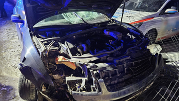 Uszkodzony samoch&oacute;d po wypadku z otwartą maską i widocznym silnikiem.