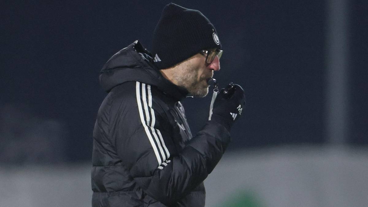 Trener Marek Papszun w czapce zimowej i kurtce z trzema paskami, trzymający gwizdek.