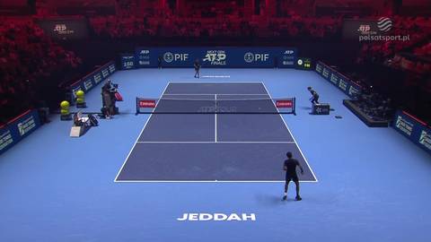 Dw&oacute;ch zawodnik&oacute;w grających w tenisa na niebieskim korcie podczas meczu.