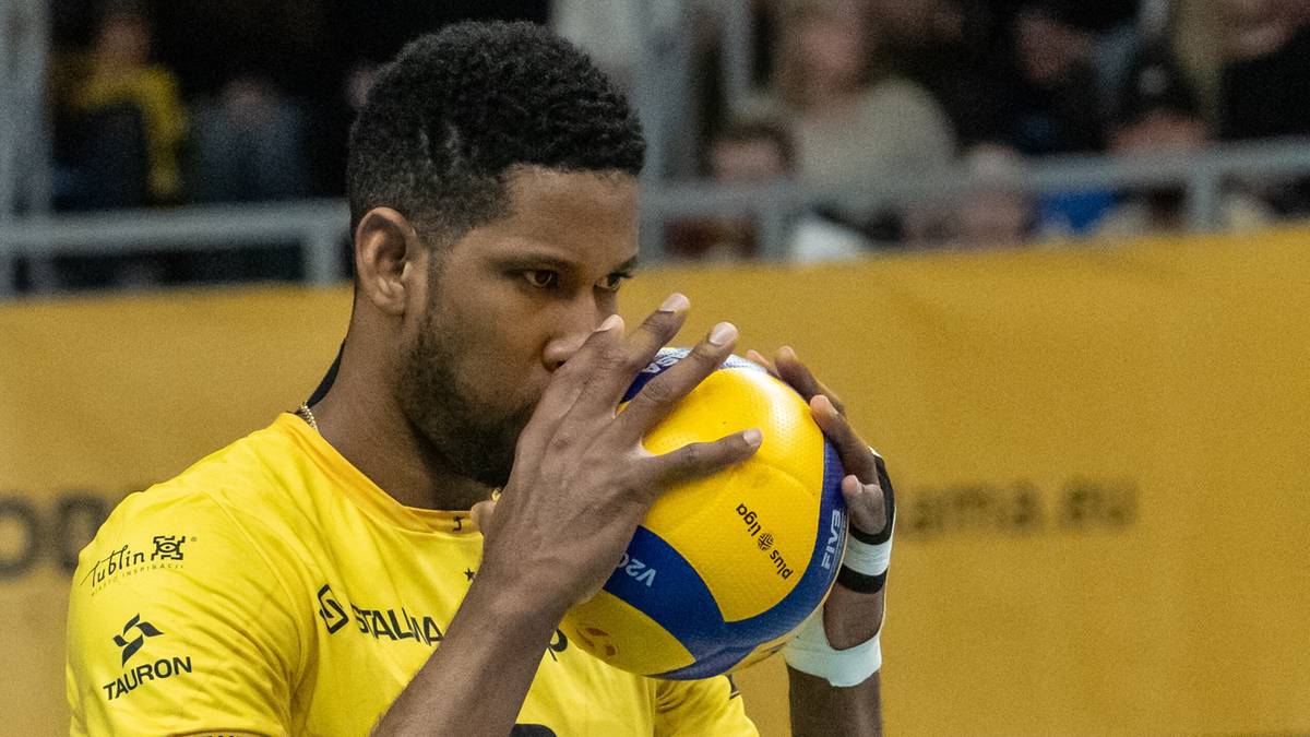 Siatkarz Aluron CMC Warty Zawiercie w ż&oacute;łtej koszulce całuje piłkę do siatk&oacute;wki.