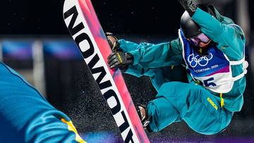 Snowboardzista wykonujący akrobację w powietrzu z deską snowboardową marki Salomon.