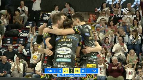 Trzech siatkarzy w czarnych strojach przytulających się na boisku podczas meczu, jeden z nich trzyma ręce na ramionach pozostałych dw&oacute;ch. Na ekranie widoczne są wyniki.