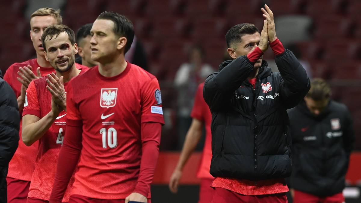 Piłkarze reprezentacji Polski w czerwonych strojach klaszczący na boisku.