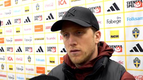 Piotr Zieliński w czapce z daszkiem i bluzie z kapturem, ubrany w kurtkę, udziela wywiadu. Na jego twarzy widać emocje. W tle znajduje się ściana z logotypami sponsor&oacute;w i herbem reprezentacji Szwecji.