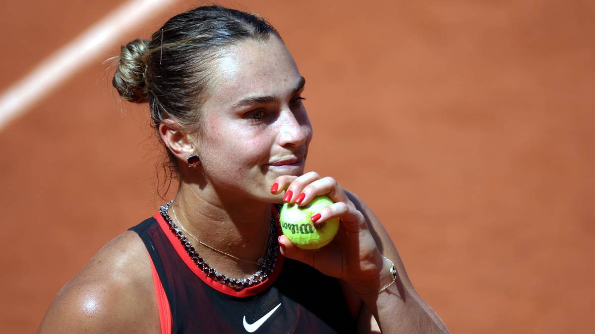 Aryna Sabalenka trzymająca piłkę tenisową na korcie ziemnym.