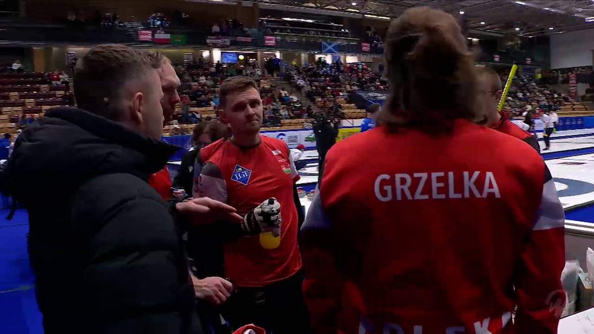 Drużyna curlingowa w czerwonych strojach omawia strategię na lodowisku