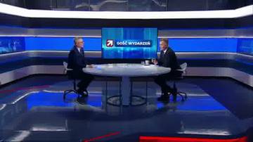 Dw&oacute;ch mężczyzn siedzi naprzeciwko siebie przy okrągłym stole w studiu telewizyjnym, na kt&oacute;rym wyświetlany jest napis "Gość Wydarzeń".