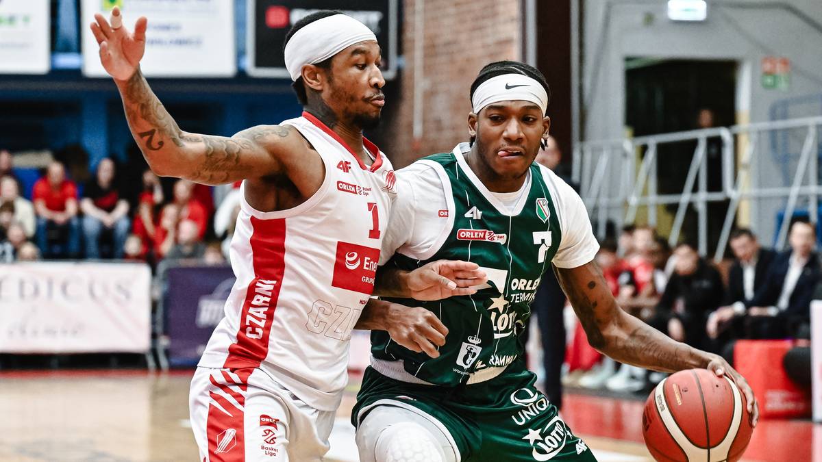 Dw&oacute;ch koszykarzy w akcji podczas meczu. Jeden zawodnik w białej koszulce z czerwonymi elementami, drugi w zielonej z białymi detalami. Obaj mają na głowach opaski.