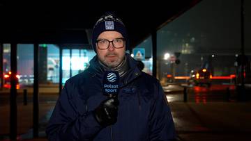 Mężczyzna w okularach i czapce zimowej trzyma mikrofon z logo Polsat Sport.