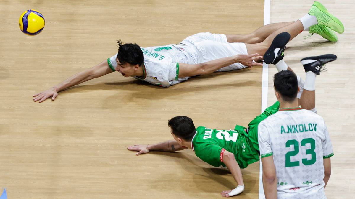 Dw&oacute;ch siatkarzy w akcji na boisku, pr&oacute;bujących odebrać piłkę.