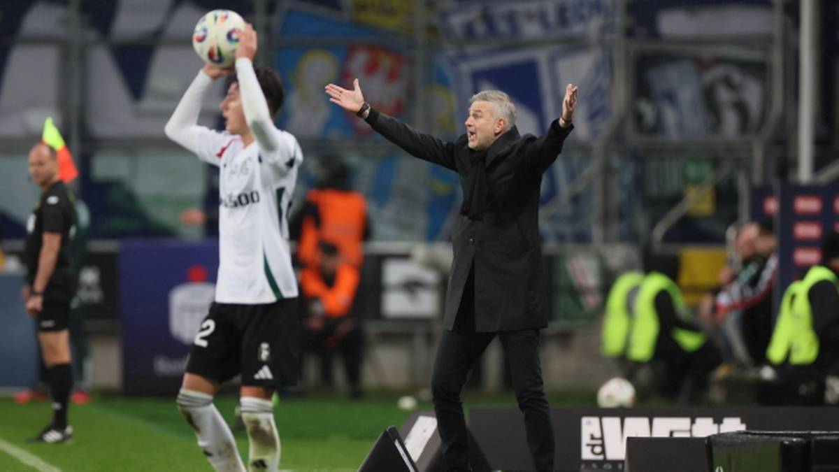 Trener piłkarski gestykuluje, a zawodnik przygotowuje się do wrzutu z autu.