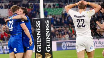 Trzech włoskich rugbyst&oacute;w przytula się po zwycięskim meczu, jeden z nich ma na plecach numer 22. W tle widać angielskiego zawodnika z numerem 22 na plecach, stojącego z rękami na głowie, oraz kibic&oacute;w na trybunach.