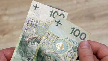 Dłonie trzymające dwie stuzłotowe banknoty.