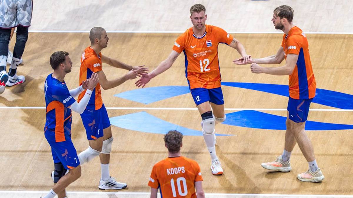 Siatkarze w pomarańczowych strojach celebrują zdobyty punkt na boisku do siatk&oacute;wki.