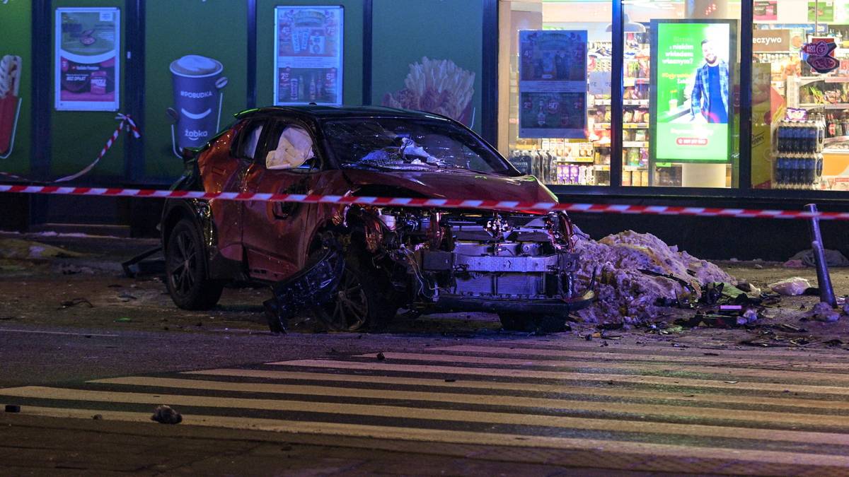 Rozbity czerwony samoch&oacute;d Ford na przejściu dla pieszych, otoczony taśmą policyjną.