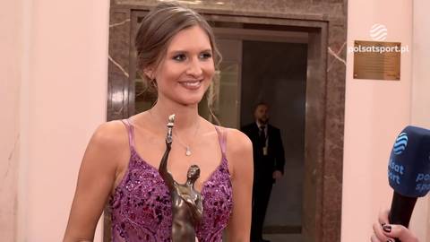 Małgorzata Leon w fioletowej sukni z cekinami trzyma statuetkę.