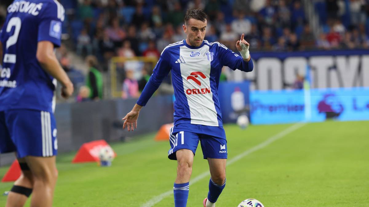 Piłkarz Wisły Płock w niebiesko-białej koszulce z numerem 11 i logo sponsora "ORLEN" na piersi, prowadzący piłkę nogą.