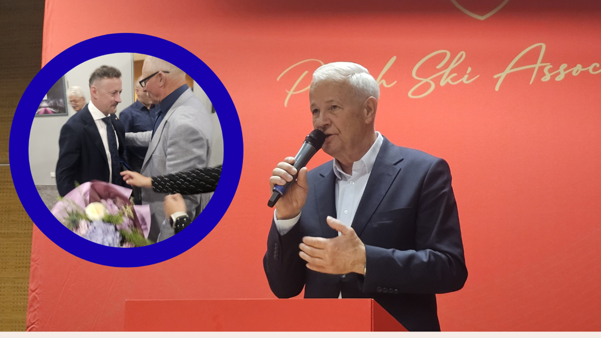 Apoloniusz Tajner przemawia do mikrofonu na tle czerwonej ściany z napisem &bdquo;Polish Ski Association&rdquo;. Obok niego, w k&oacute;łku, widoczni są inni mężczyźni.