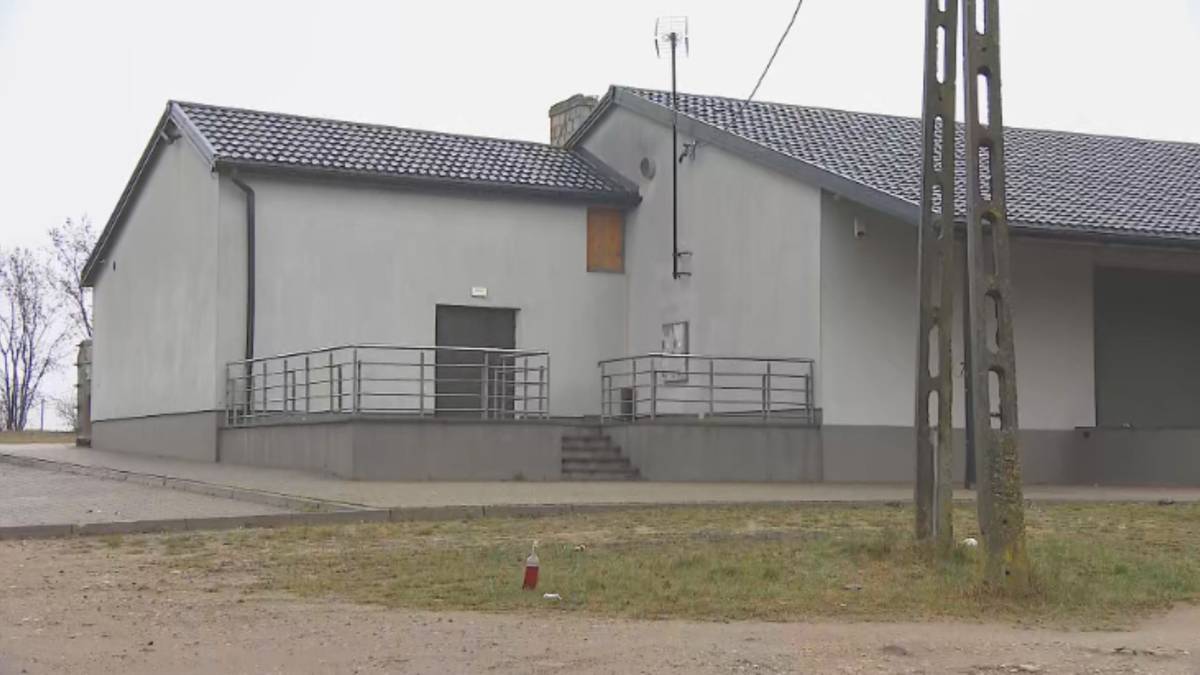 Budynek dyskoteki z szarym dachem i białymi ścianami, z podestem i schodami prowadzącymi do drzwi.