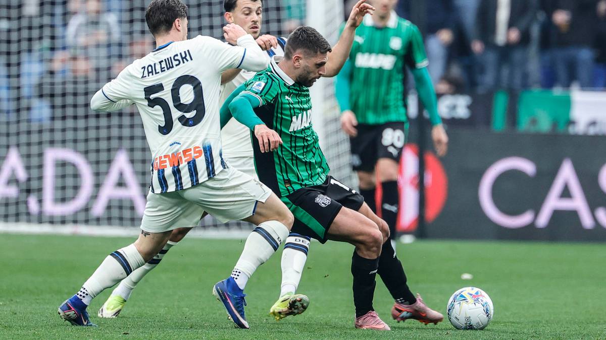 Piłkarze walczą o piłkę na boisku podczas meczu.