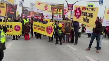 Grupa protestujących os&oacute;b na drodze trzymająca ż&oacute;łte banery z napisami "S7 STOP" i "Dolna Wilga bez betonu".
