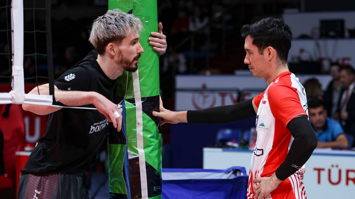 Dw&oacute;ch siatkarzy rozmawia przy siatce podczas meczu siatk&oacute;wki.