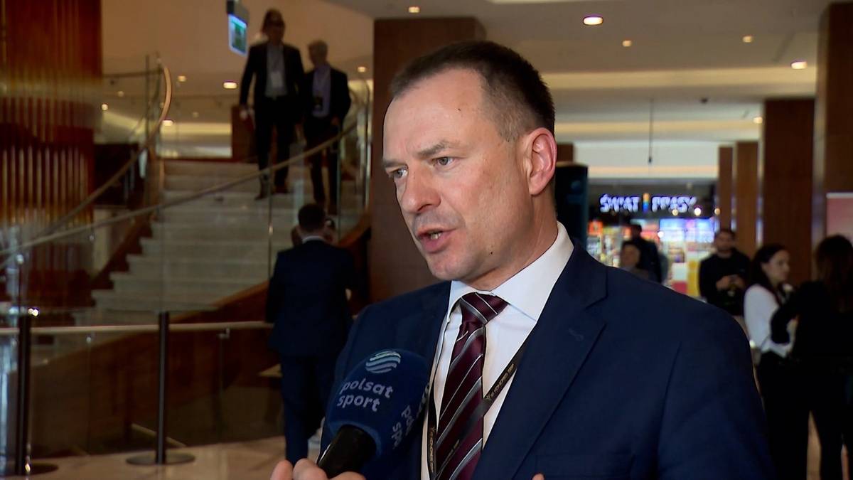 Mężczyzna w garniturze z krawatem udziela wywiadu przed mikrofonem Polsat Sport.