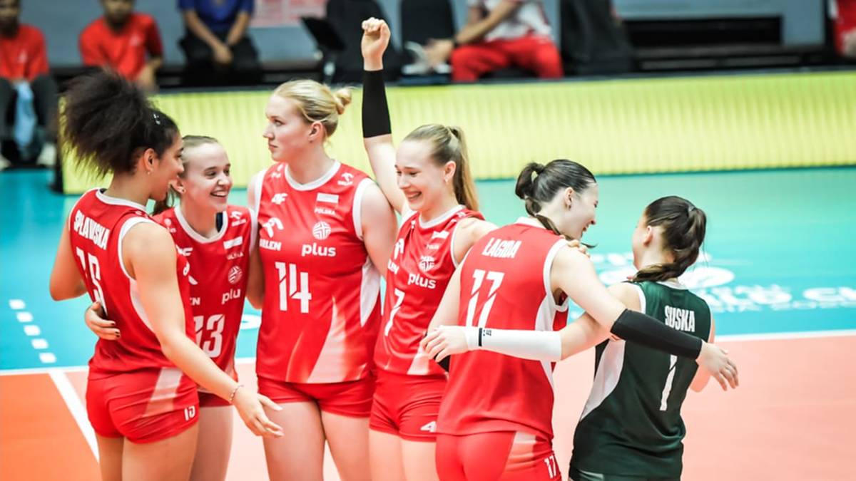 Siedem zawodniczek z drużyny siatkarskiej w czerwonych strojach cieszy się ze zwycięstwa, przytulając się i unosząc ręce.