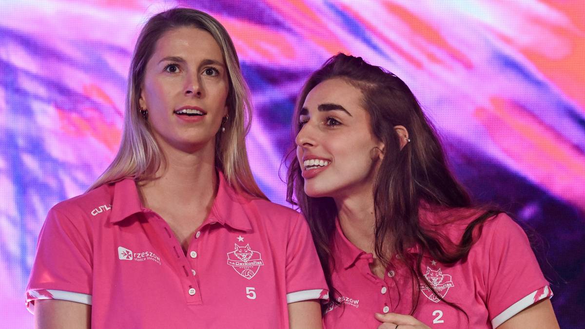 Dwie zawodniczki sportowe w różowych koszulkach patrzą w stronę obiektywu, jedna z nich uśmiecha się.