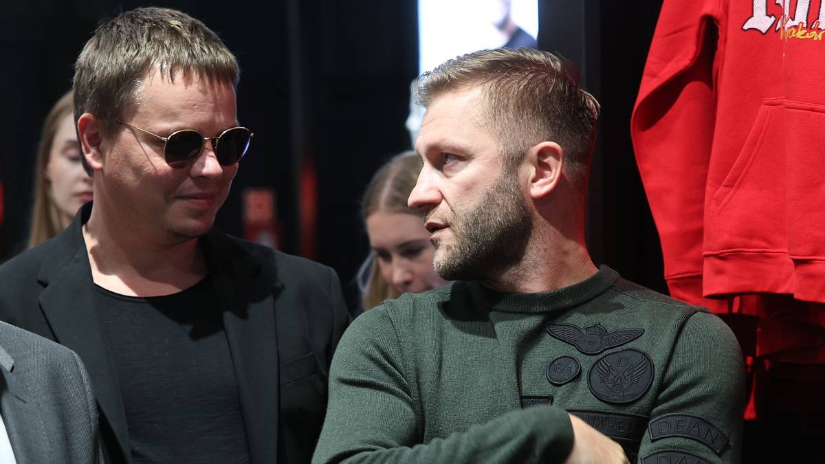 Dwóch mężczyzn rozmawia, jeden w okularach przeciwsłonecznych, drugi z brodą.