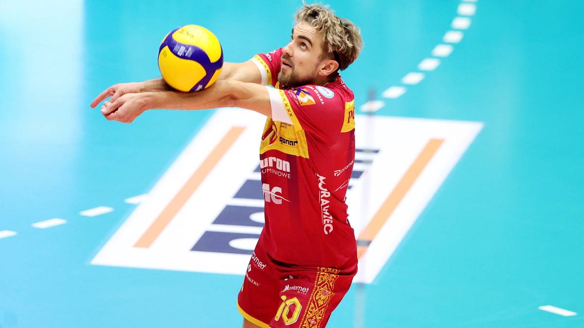 Siatkarz w czerwonej koszulce z numerem 10 zagrywa piłkę do siatkówki.