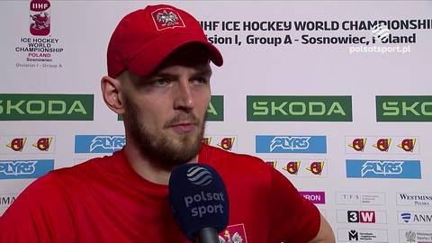 Hokeista z brodą w czerwonej czapce i czerwonej koszulce z logo Polsatu Sport, udzielający wywiadu.