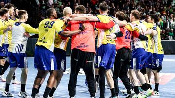 Drużyna piłkarzy ręcznych w ż&oacute;łto-niebieskich strojach świętuje zwycięstwo na boisku, stojąc w grupie.