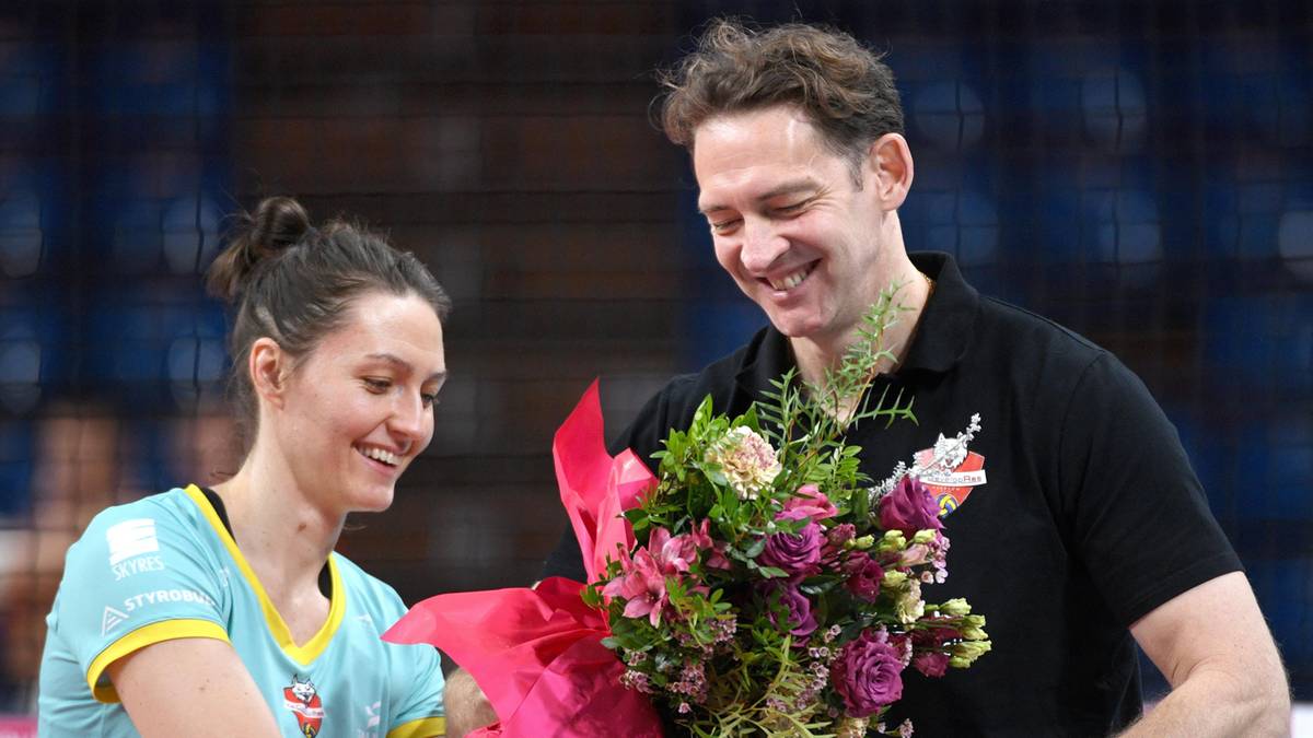 Kobieta i mężczyzna uśmiechają się, trzymając bukiet kwiat&oacute;w.