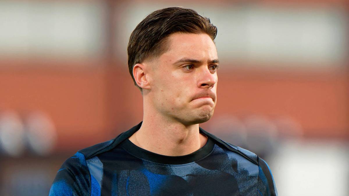 Mężczyzna w niebiesko-czarnej koszulce sportowej z zamyśloną miną.