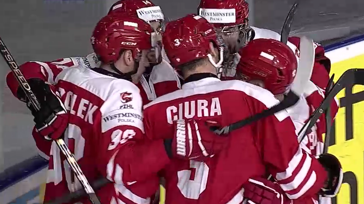 Grupa hokeistów w czerwonych strojach świętuje zwycięstwo, trzymając się blisko siebie.
