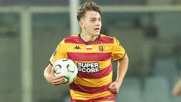 Młody piłkarz w ż&oacute;łto-czerwonym stroju biegnie z piłką.