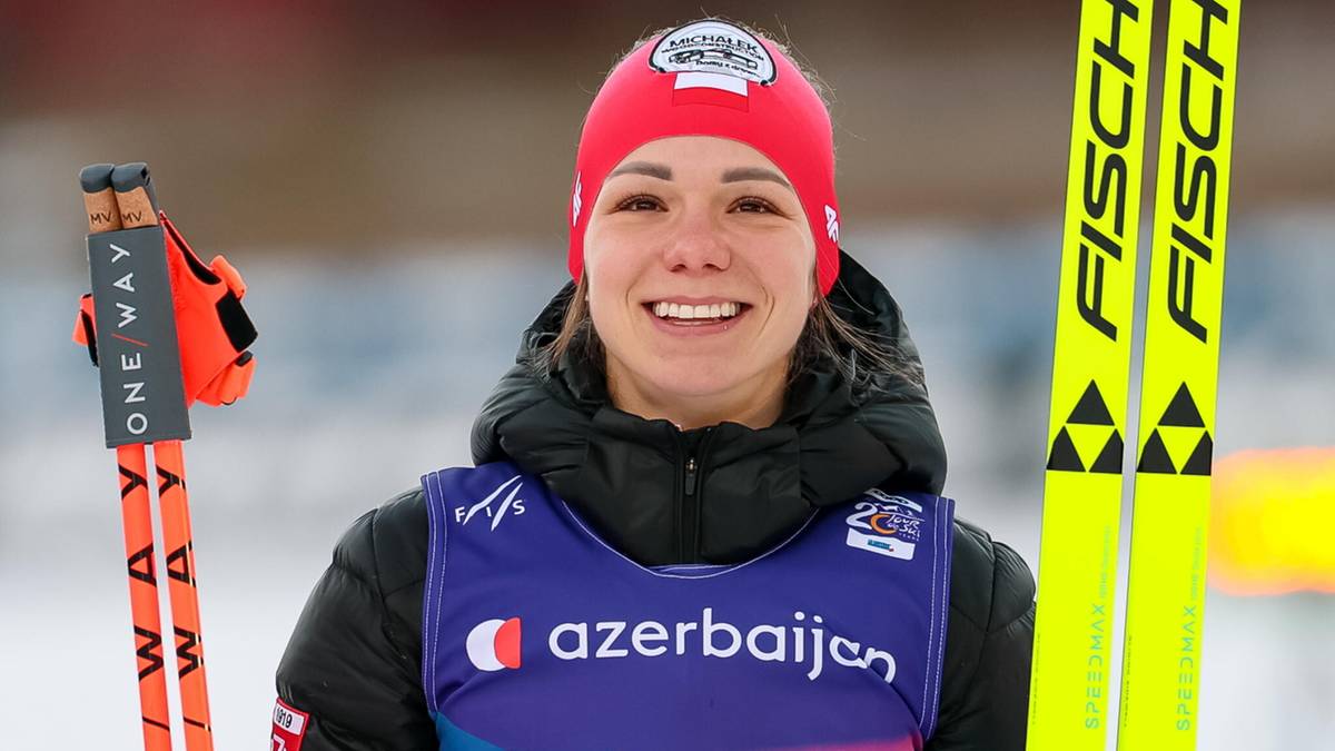 Narciarka biegowa z numerem startowym 49 na kamizelce, trzymająca kijki i narty.