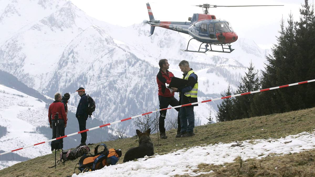 Grupa ratownik&oacute;w i narciarki na g&oacute;rskim stoku z helikopterem w tle.