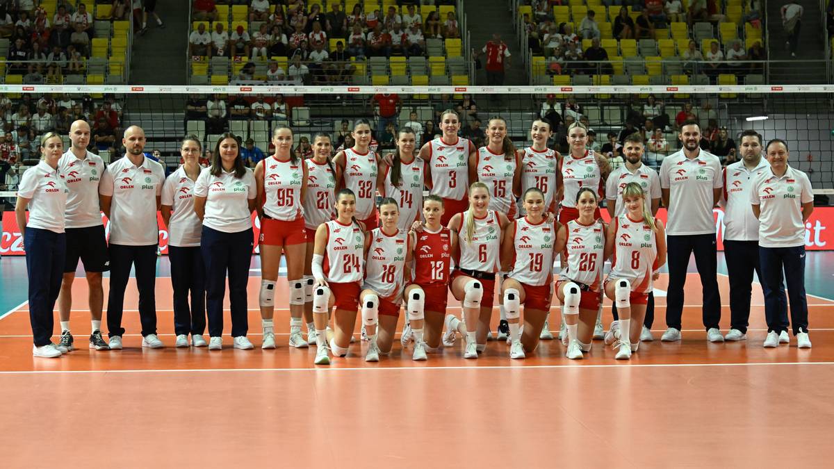 Drużyna siatkarek Polski w strojach sportowych pozuje do zdjęcia na boisku.